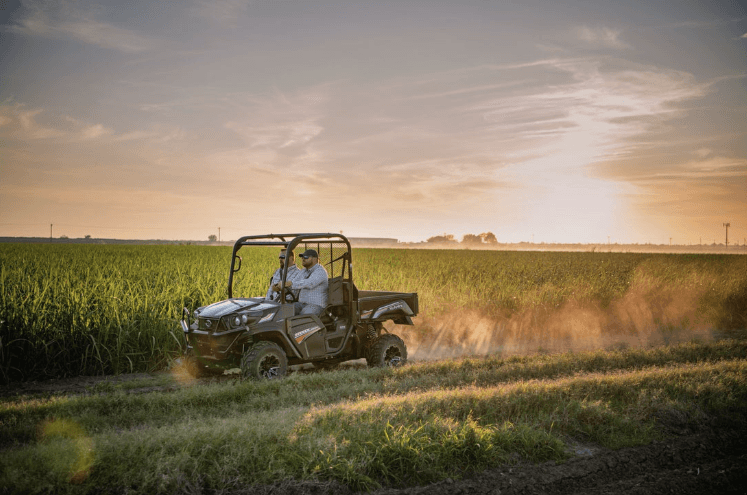 Men driving down a dirt road in a Kubota Utility Vehicle