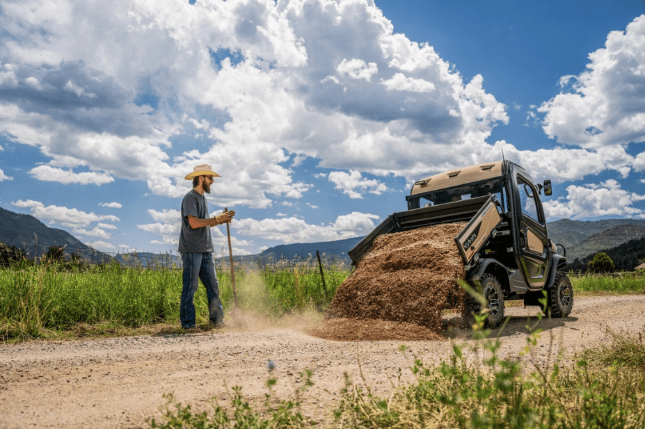 Man using the Kubota utility vehicle cargo bed to dump out dirt