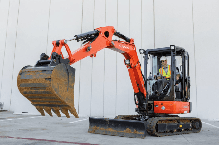 Compact Excavator parked outside of warehouse  